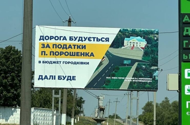 Білборд у Городківці з написом «Дорога будується за податки П. Порошенка» на тлі сільської дороги